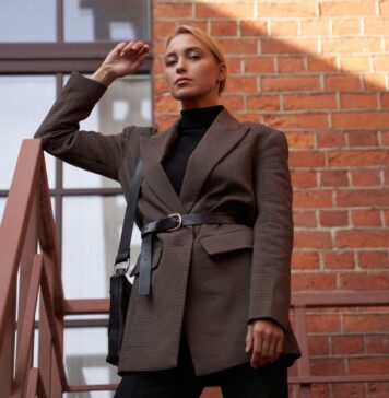 Jak nosić nerkę damską po trzydziestce, żeby wyglądać z klasą? Elegancka kobieta w marynarce pozuje na schodach przy ceglanej ścianie