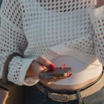 Kobieta po trzydziestce w casualowym stroju z nerką, sprawdza telefon