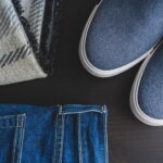 Flat lay: jeansy, niebieskie sneakersy i kraciasty szalik