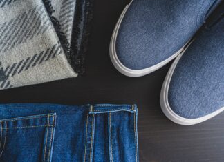 Jak stworzyć elegancką stylizację z jeansami dzięki odpowiednim torebkom, paskom i delikatnej biżuterii Flat lay: jeansy, niebieskie sneakersy i kraciasty szalik