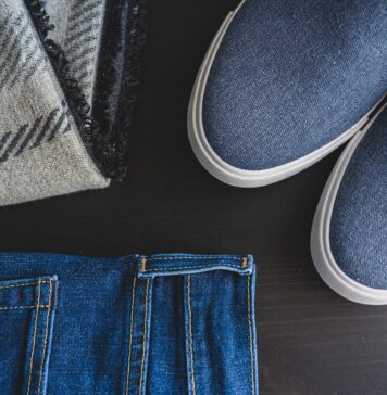 Jak stworzyć elegancką stylizację z jeansami dzięki odpowiednim torebkom, paskom i delikatnej biżuterii Flat lay: jeansy, niebieskie sneakersy i kraciasty szalik
