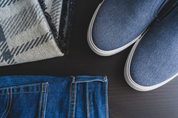 Flat lay: jeansy, niebieskie sneakersy i kraciasty szalik
