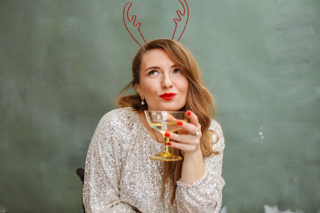 Kobieta w cekinowym topie z czerwonymi ustami trzyma drinka w pomieszczeniu Kobieta w cekinowym topie z czerwonymi ustami trzyma drinka w pomieszczeniu