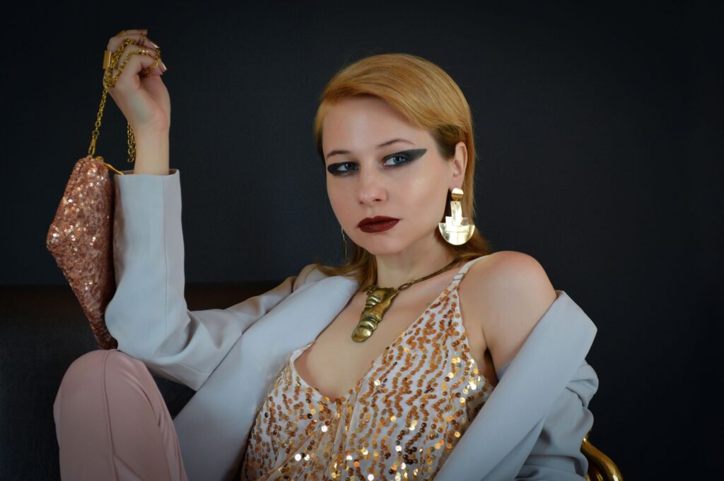 Modelka w cekinowej bluzce i marynarce z torebką na czarnym tle
