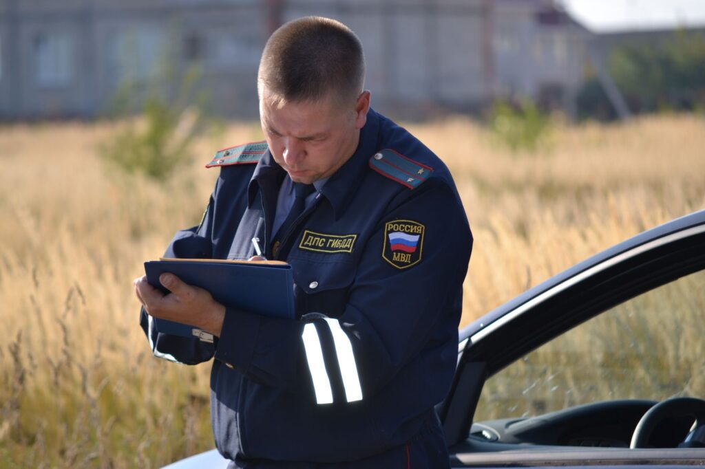 Policjant w mundurze robi notatki obok samochodu na polu