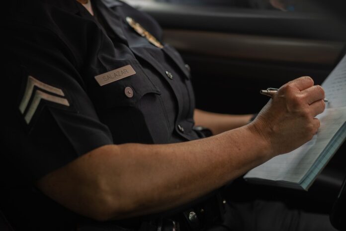 Policjant zapisujący zgłoszenie kradzieży w notatniku w radiowozie