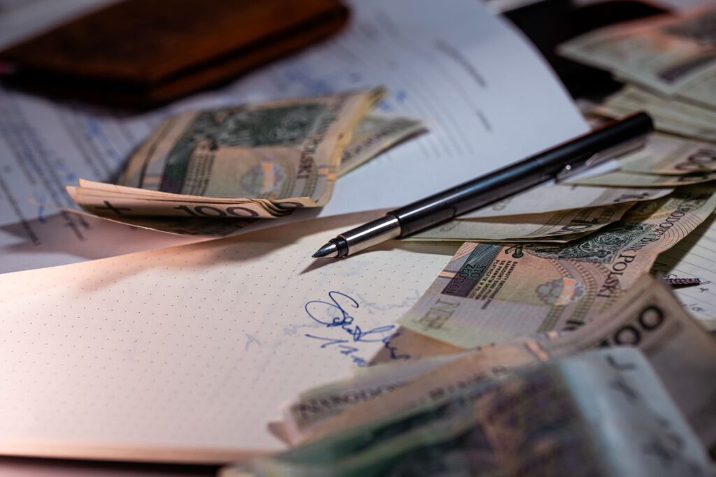 Polskie banknoty, dokumenty i długopis na biurku widziane z góry